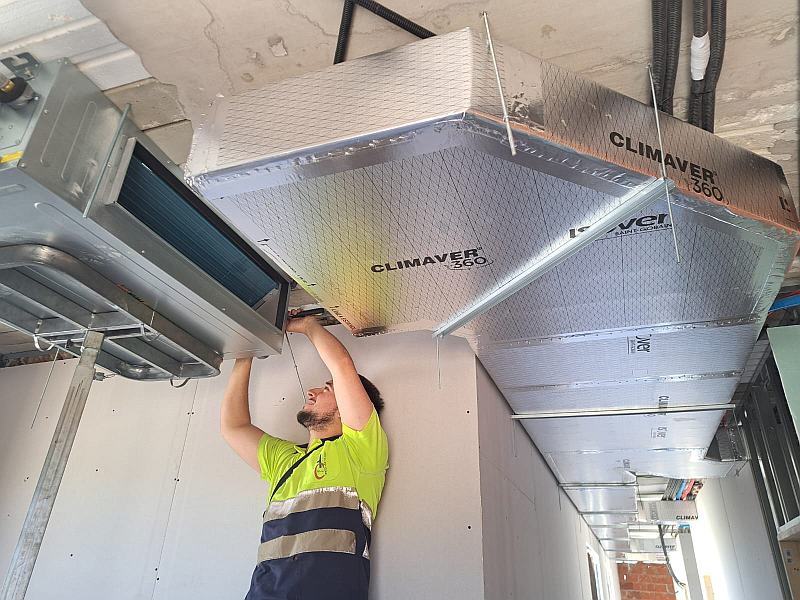 Técnico realizando la instalación de aire acondicionado por conductos en una vivienda de obra nueva